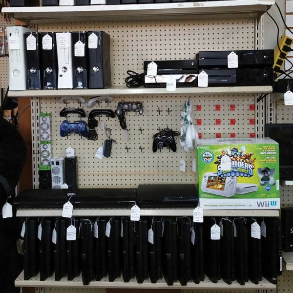 video game consoles on a shelf with price tags