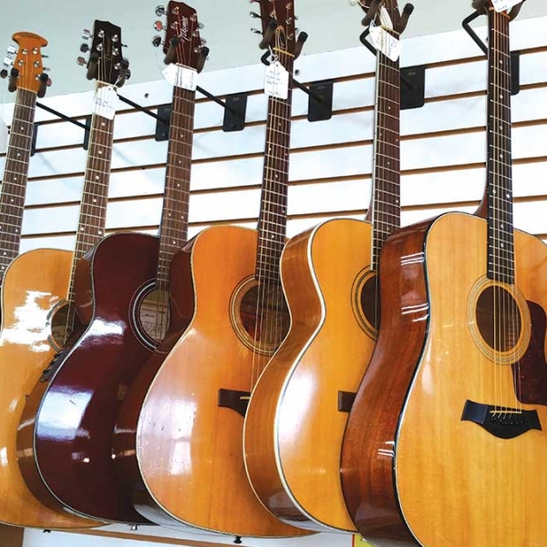 Seven Acoustic Guitars And A Banjo Mounted On Shop Wall